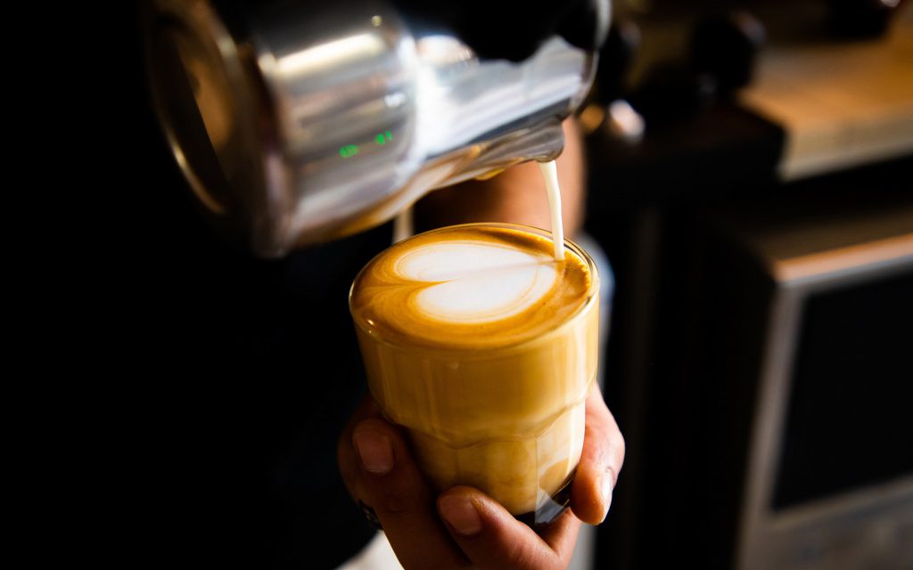 A barista pours latte art onto a coffee in Japan.
