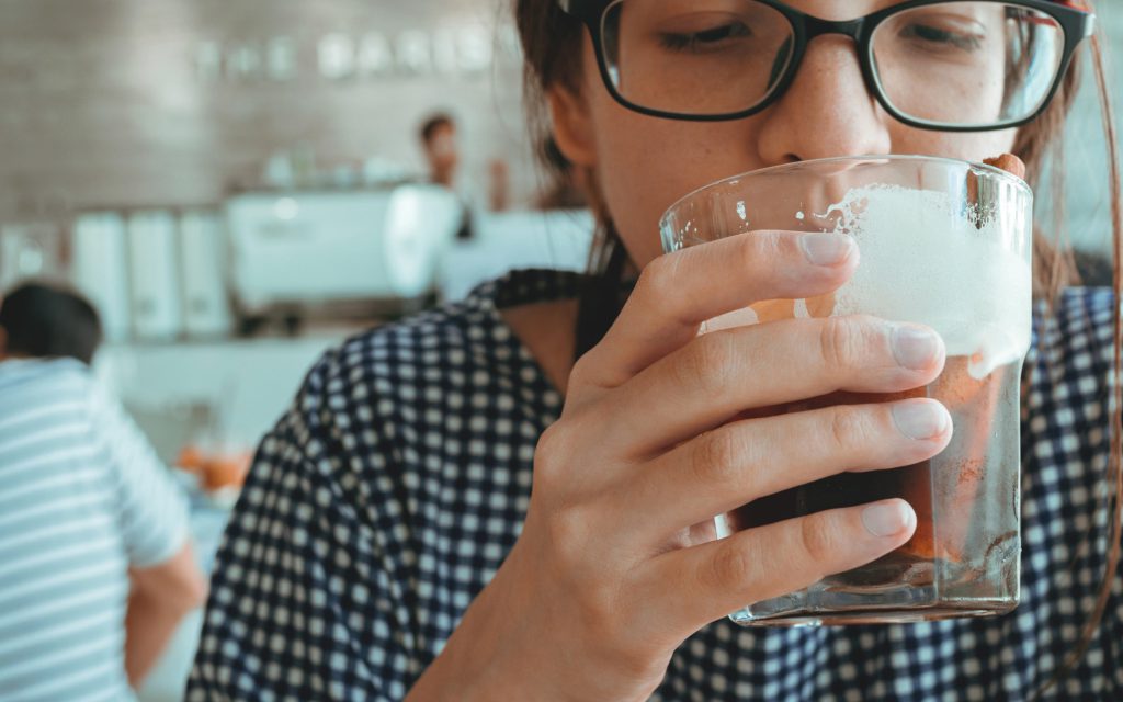 A woman drinks sustainable coffee in a coffee shop.