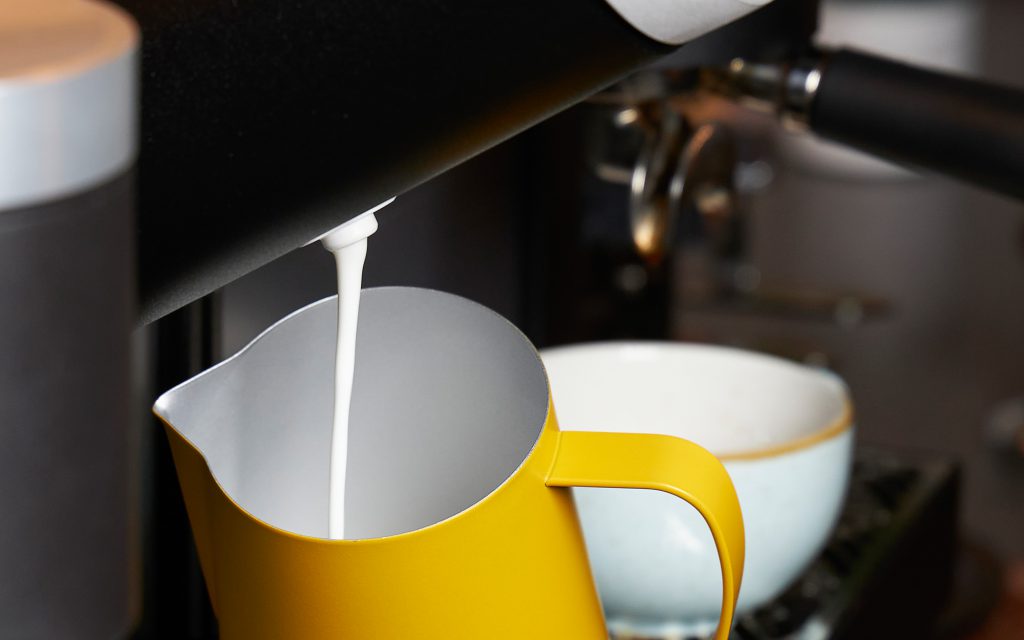 The Heylo Milk Module dispenses milk foam into a jug.