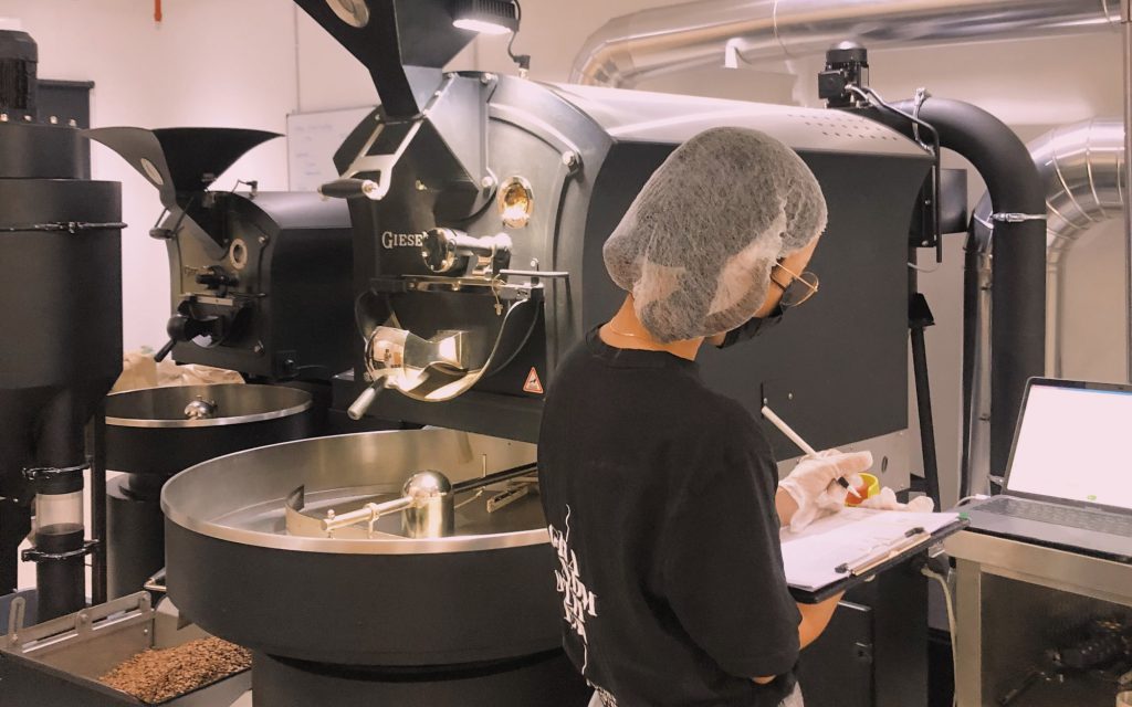 A coffee professional records data on a Giesen roaster.