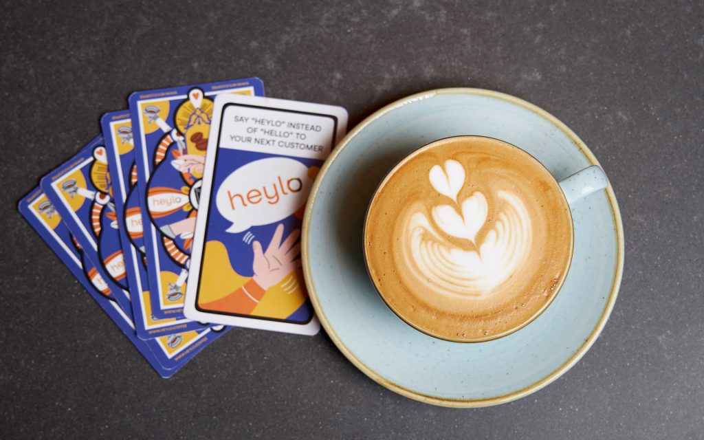 Latte art on a coffee alongside playing cards.